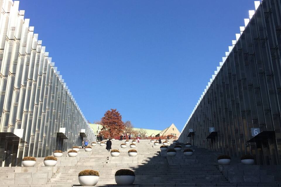 A staircase leading up to a modern building with a unique geometric facade.