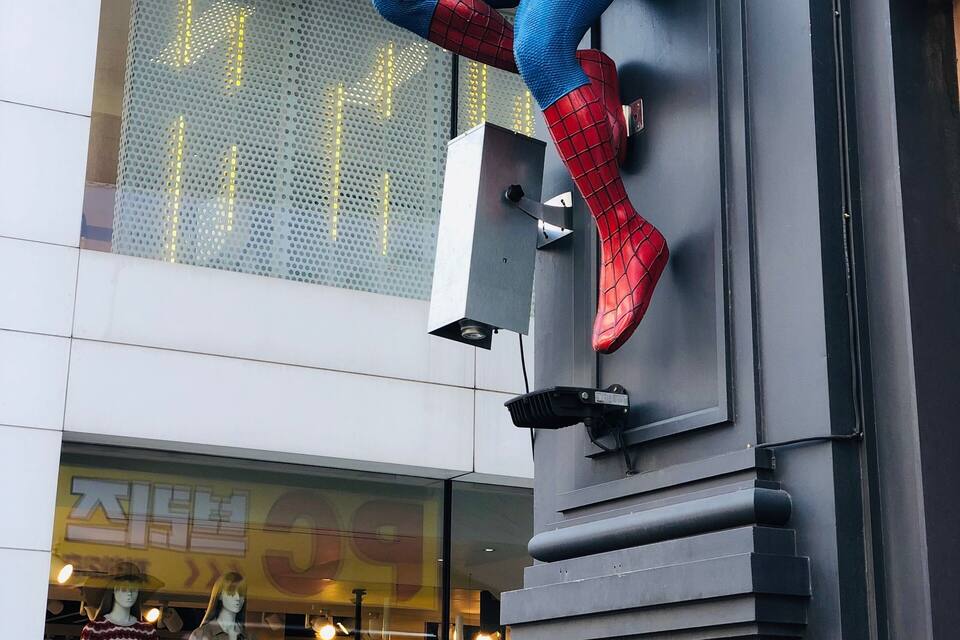 En staty av Spider-Man som klättrar på en byggnadsfasad.