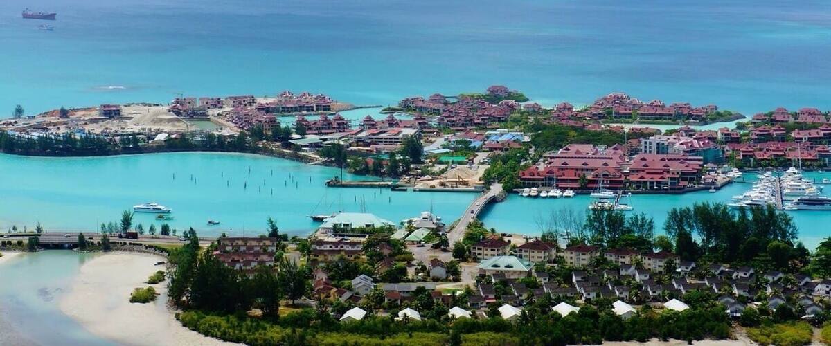 A coastal resort with a marina, clear turquoise waters, and a prominent mountain in the background.
