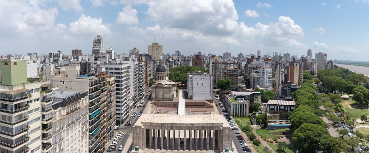 A cityscape with a prominent historical building in the center, surrounded by modern high-rise buildings and a river in the background.