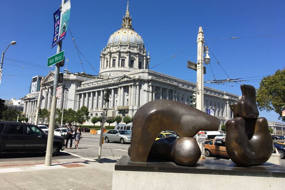 A large classical building with a dome and columns, a street sign reading "Van Ness", and a modern sculpture on a pedestal.