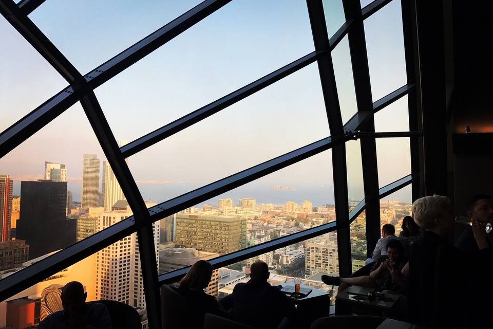 A cityscape viewed through a large window with a metal framework.