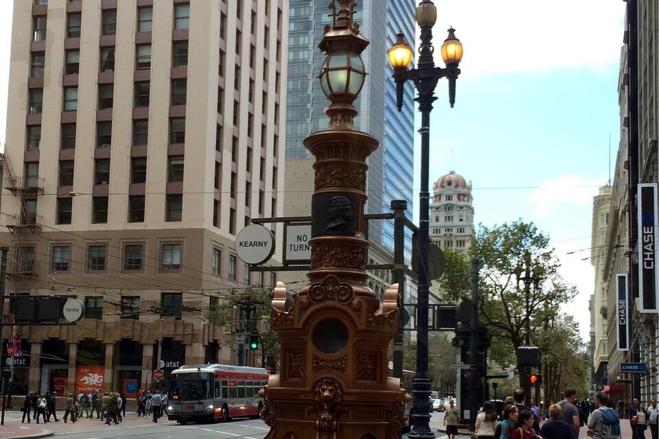 Una calle con un farol decorativo, un autobús y edificios altos.