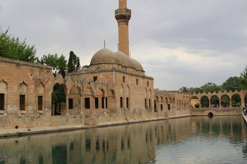 Una mezquita con un minarete alto y su reflejo en el agua.