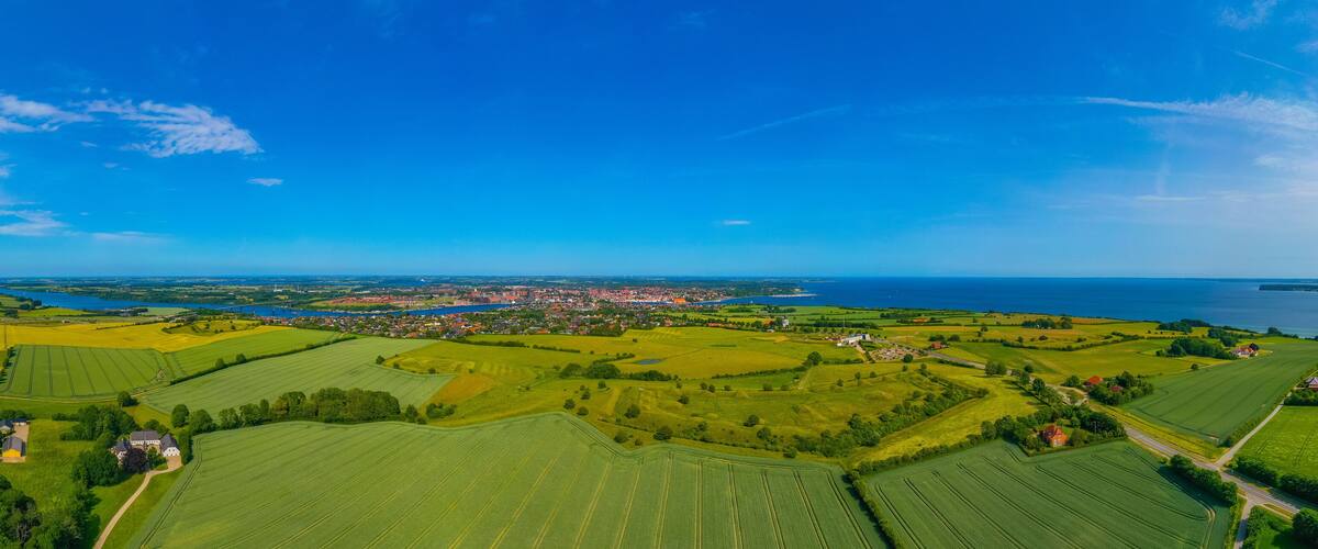 A rural landscape with fields, a small town, and a body of water.
