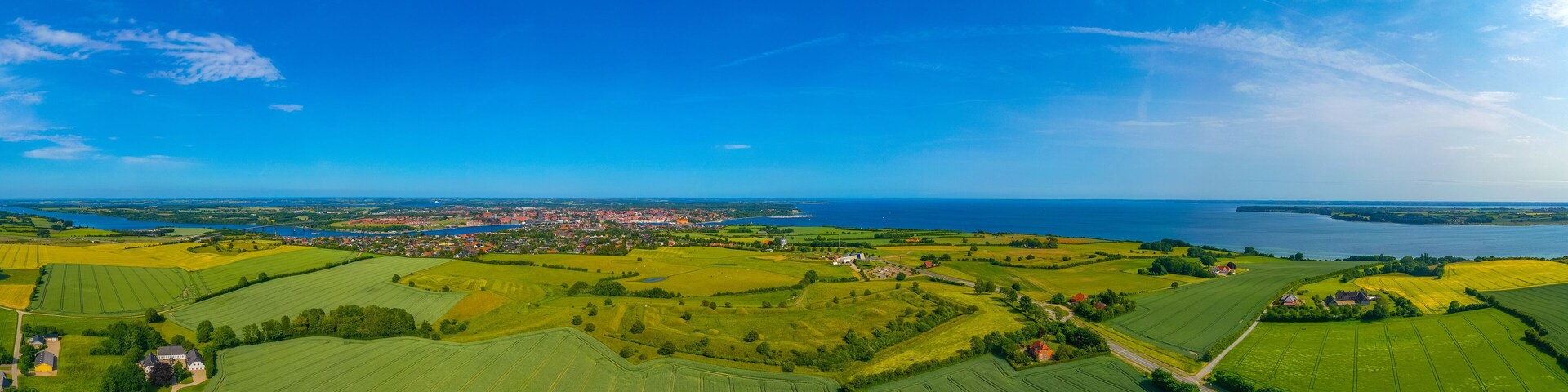 A rural landscape with fields, a small town, and a body of water.