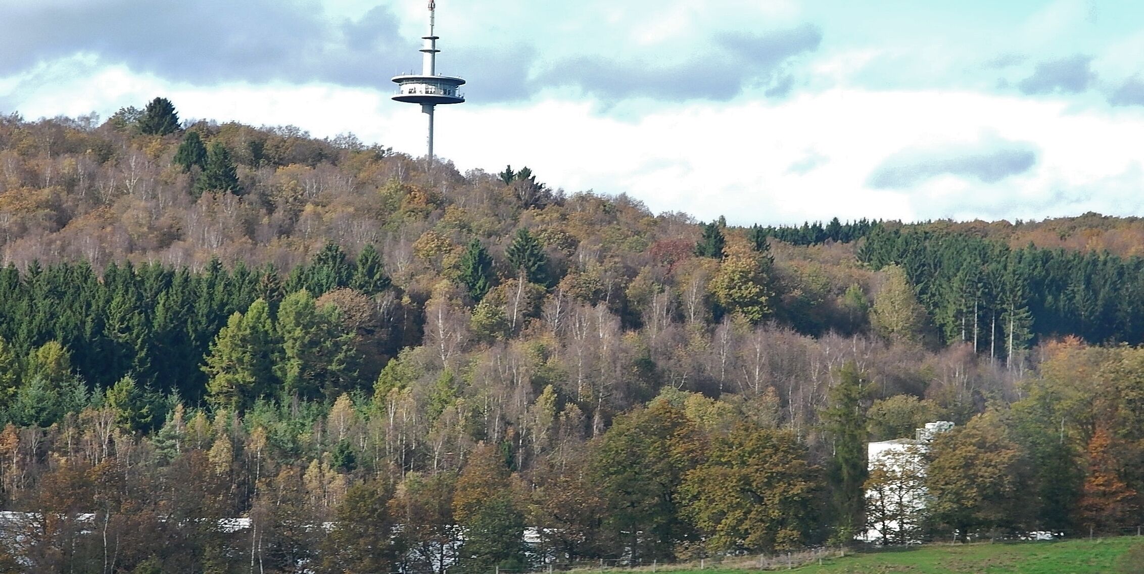 A tower on a hill with autumn-colored trees.