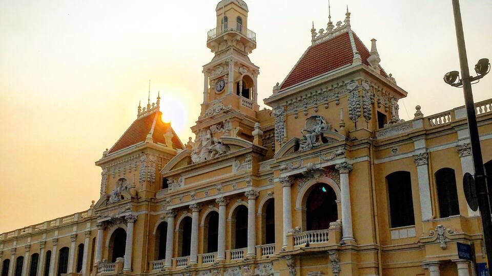 A historic building with ornate architecture, a prominent clock tower, and a flag.