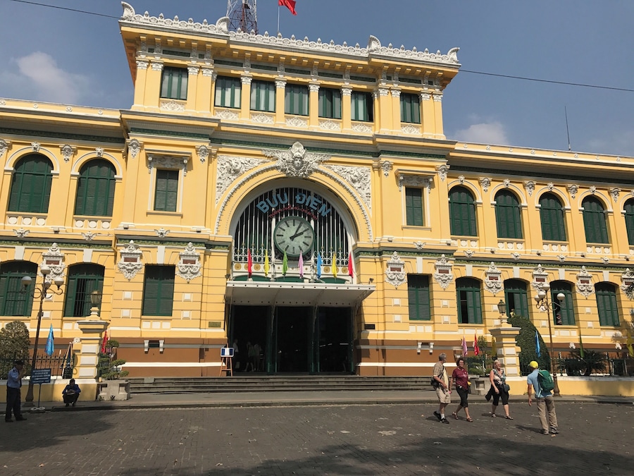 A yellow building with green shutters and a clock.
