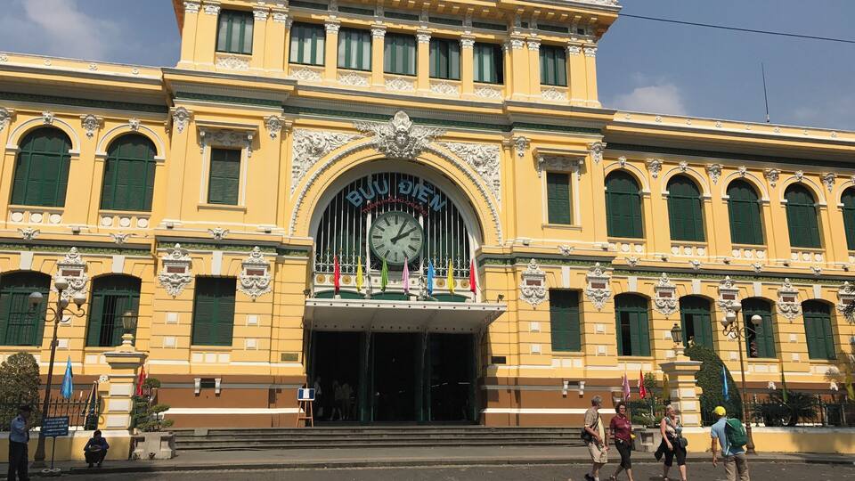 A yellow building with green shutters and a clock.