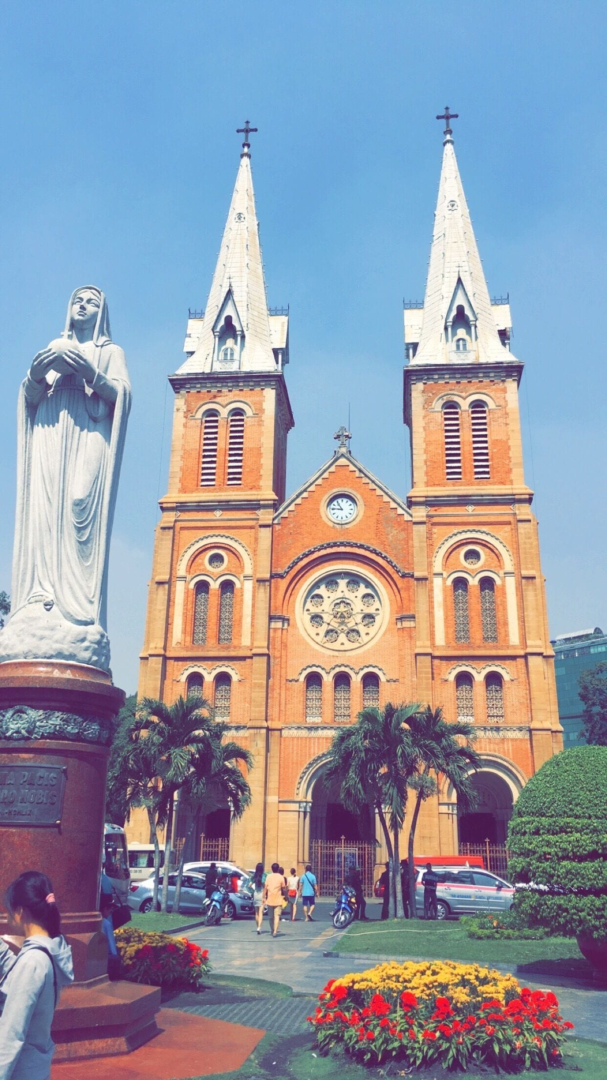 A large church with two tall spires and a statue in front.
