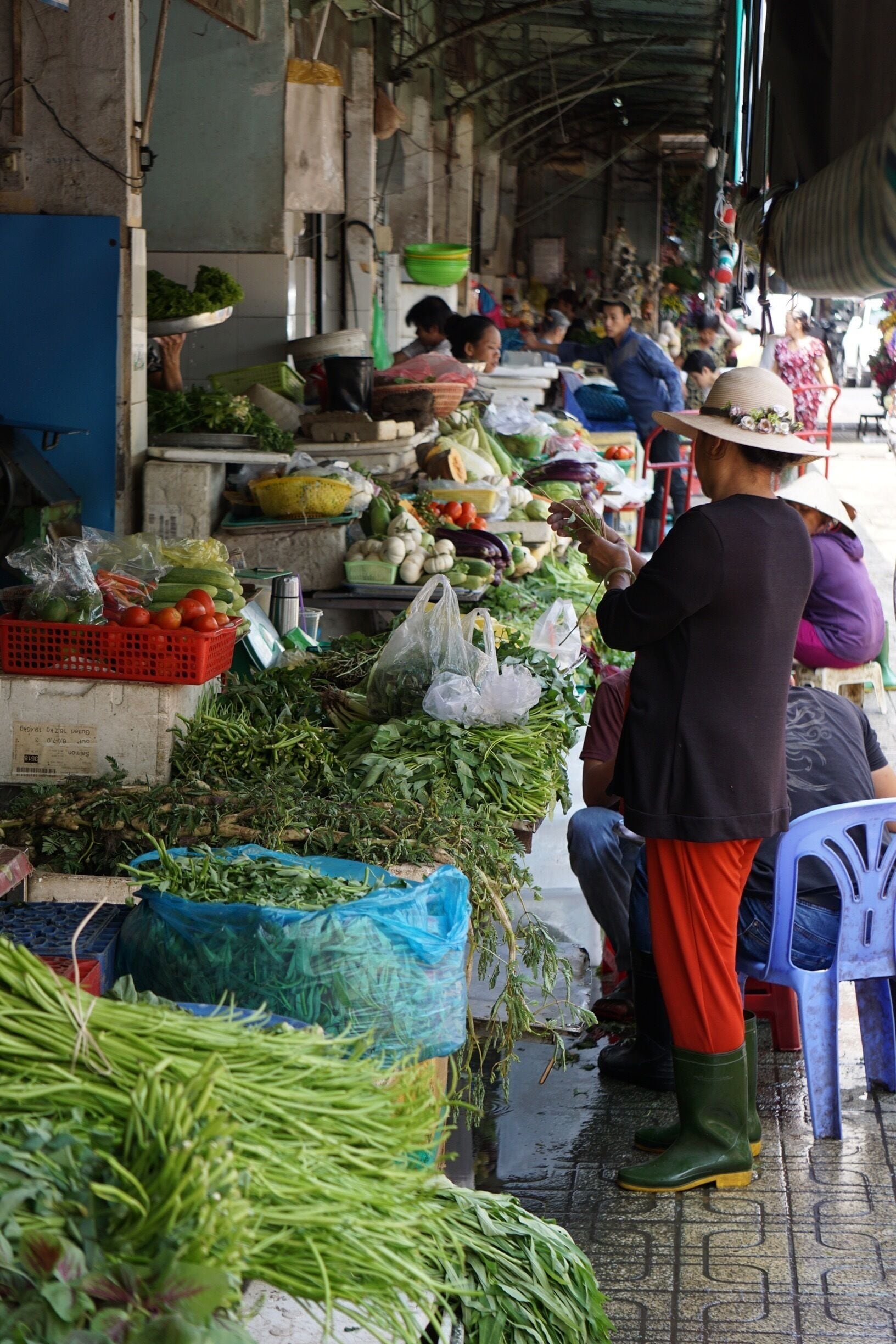 A bustling outdoor market with various fresh vegetables and fruits displayed on tables and in baskets.