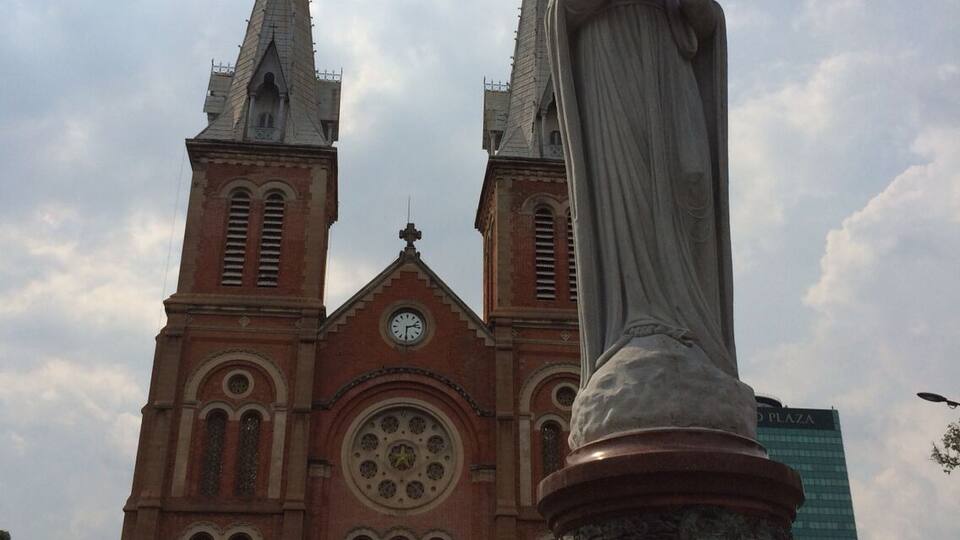 A church with two spires and a statue in front.