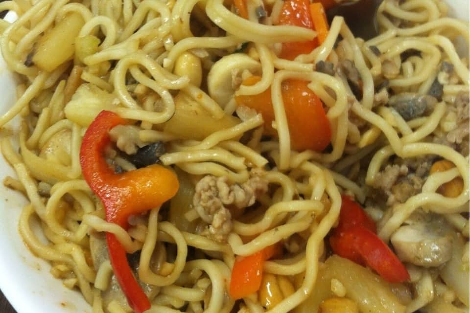A bowl of noodles with vegetables and meat.