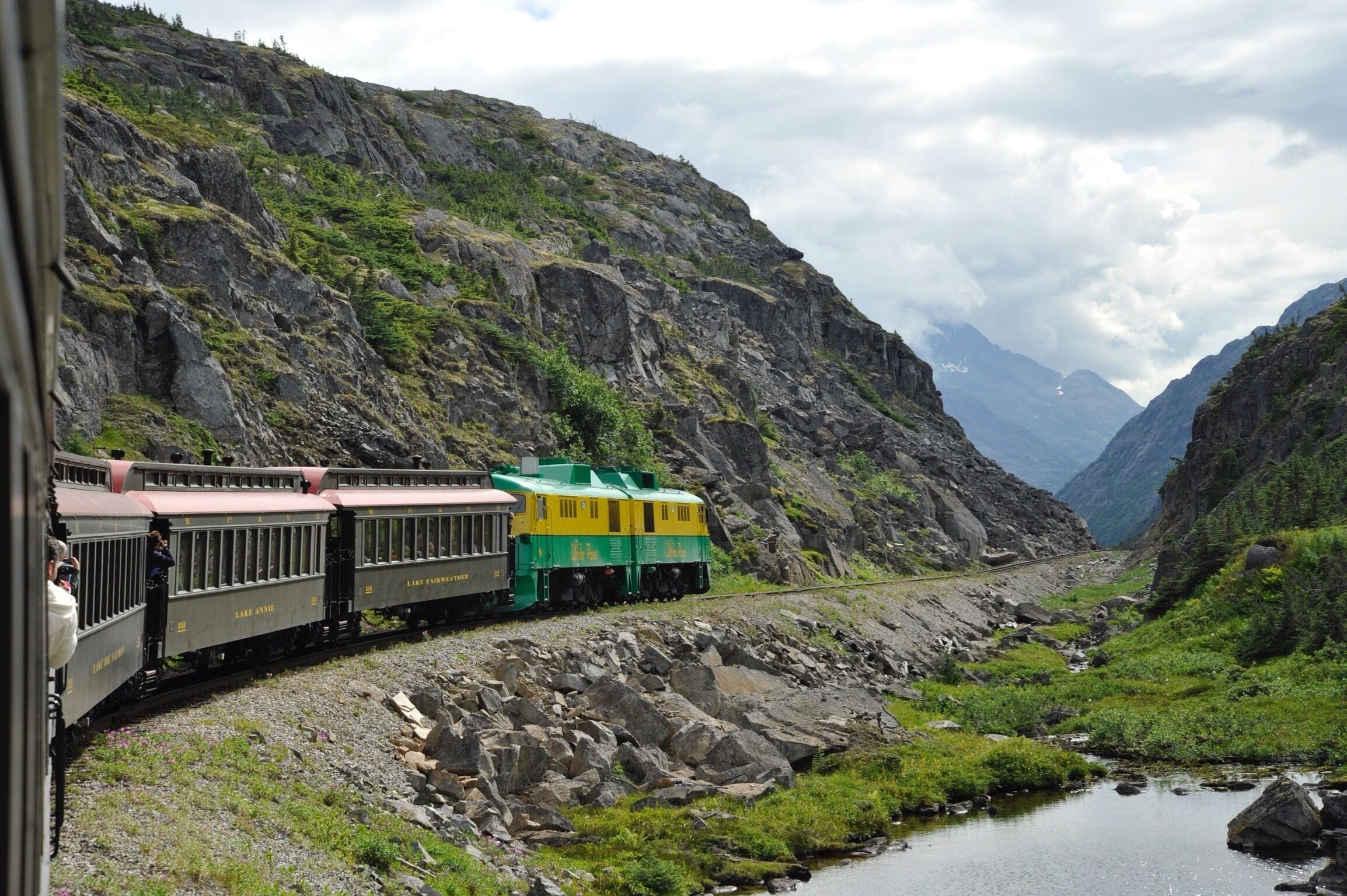 A train traveling through a mountainous area with a river and rocky terrain.