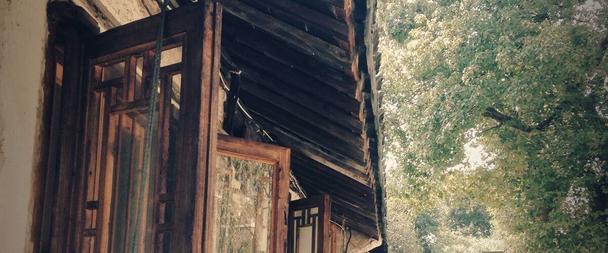 A traditional wooden building with a sloped roof, a wooden door, and a window with a decorative frame.