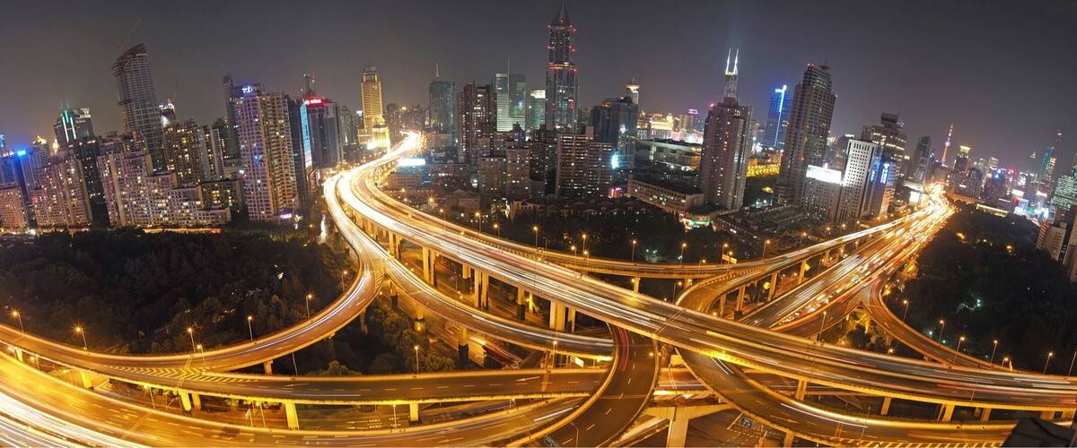 A nighttime cityscape with a complex network of highways and illuminated skyscrapers.