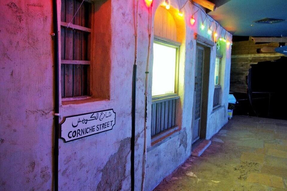 A building with a sign reading "Corniche Street" in Arabic.