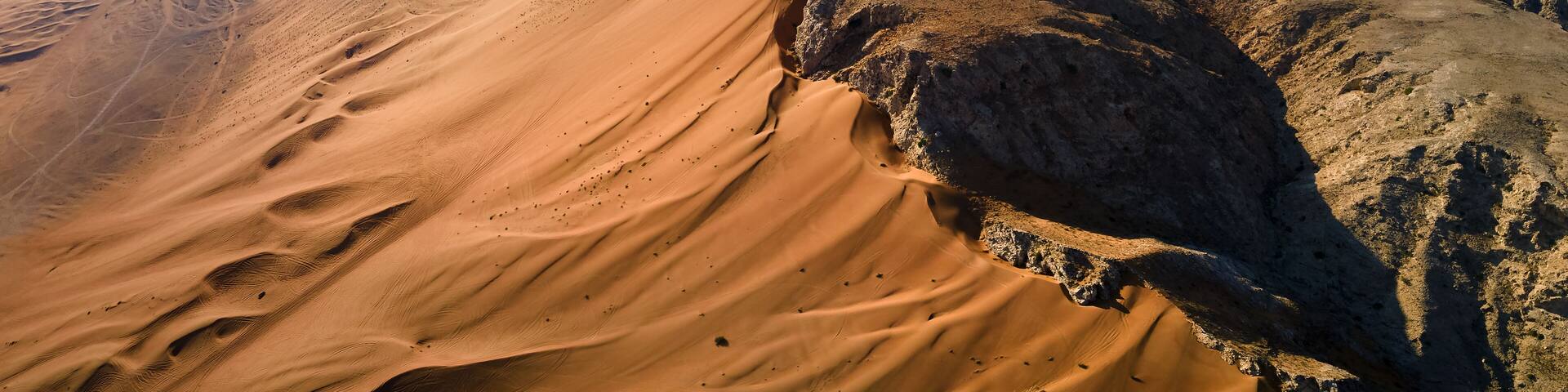 A vast desert landscape with prominent sand dunes and rocky outcrops.