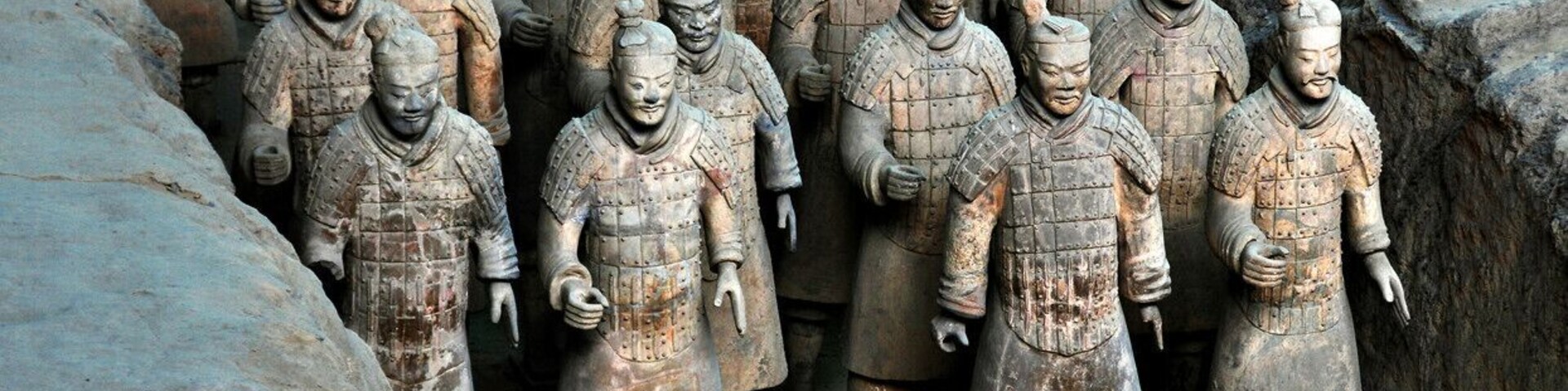 Um grande grupo de soldados de terracota em formação, posicionados em uma passagem estreita.