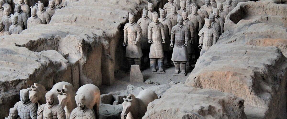 Terracotta soldiers in a formation, arranged in rows and columns, with a horse in the center.