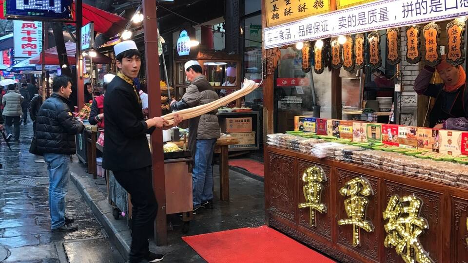A street market with food stalls, including one with a sign in Chinese characters.