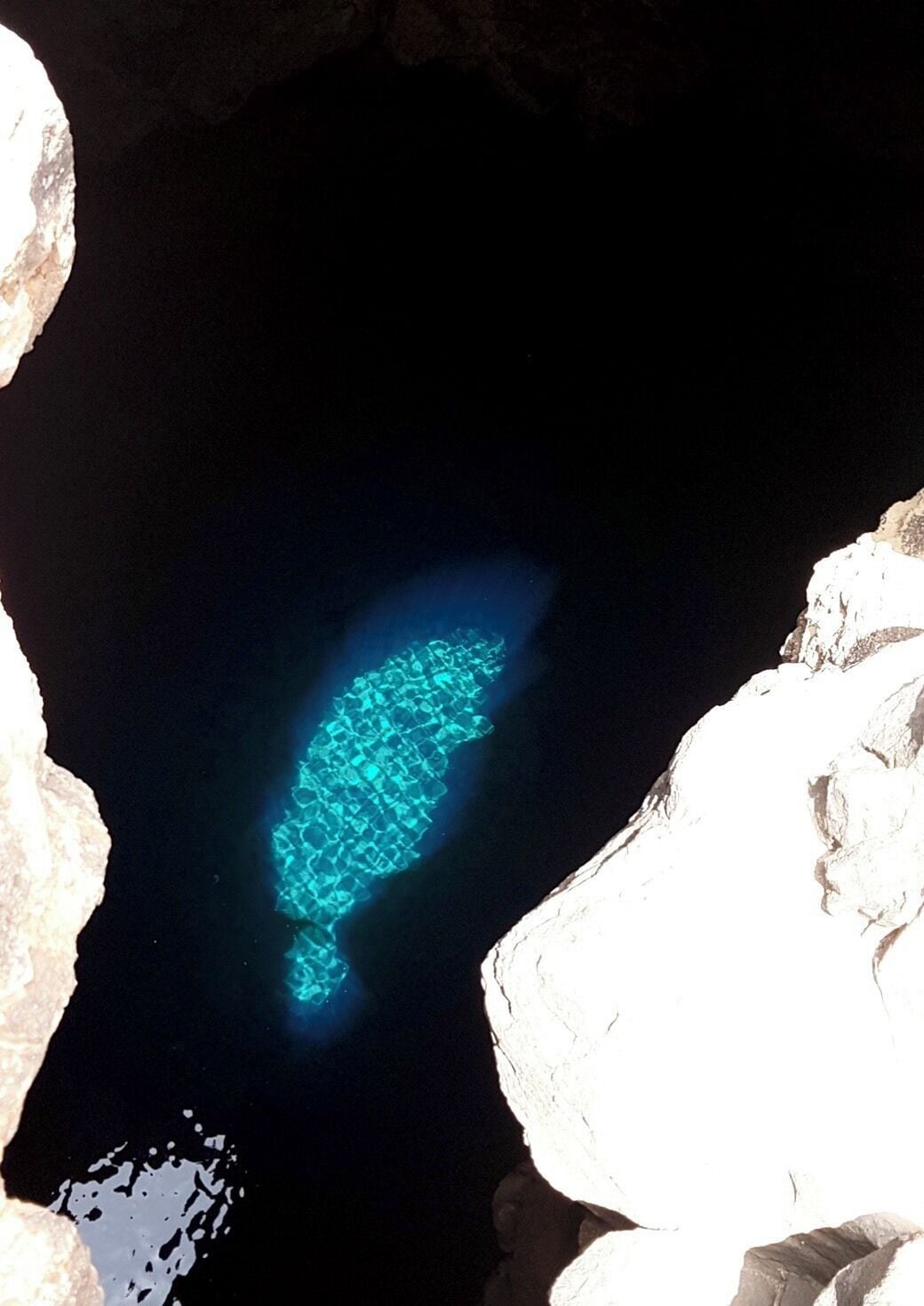 A cave with a blue light illuminating a fish shape on the wall.