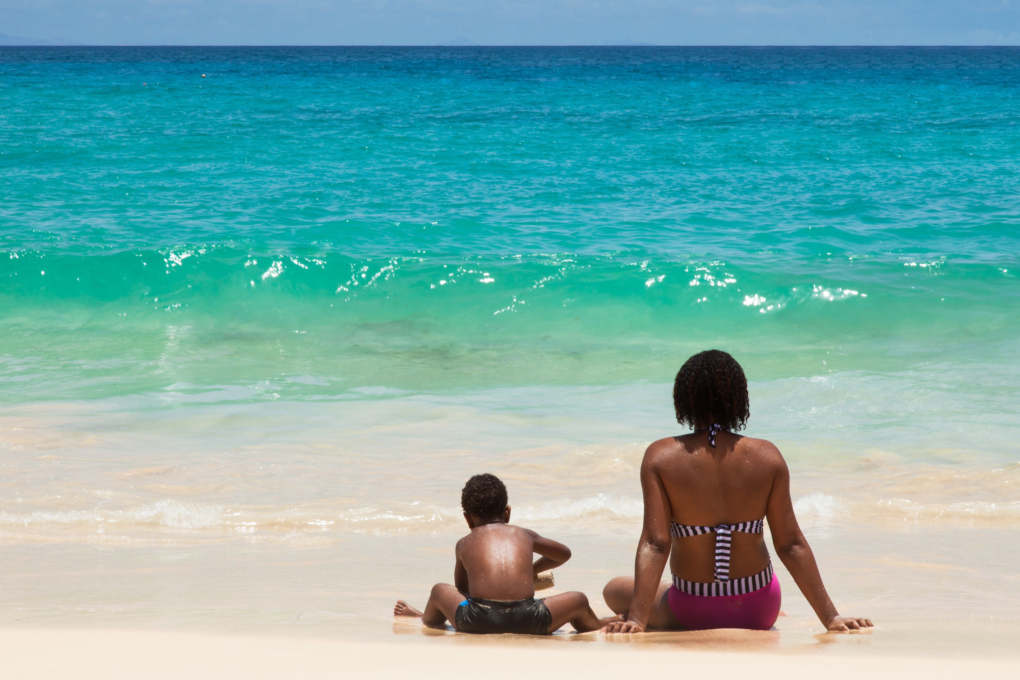 People seated on the sand in front of the Ocean at Santa Maria B