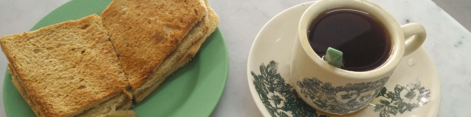 #TroveOn in Singapore. Kaya Toast with Butter and a Tea-O at the Ya Kun Kaya Toast location in Far East Square. This is a typical Singapore an breakfast which I'm having as an appetizer for lunch. Lol. They put a thick slab of butter in the middle on two breads. It's quite a heavy fatty breakfast but you'll just sweat it off from the Singapore an heat.