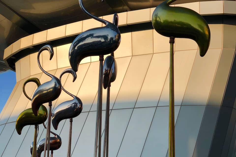 A modern building with a reflective glass facade and decorative metal sculptures.