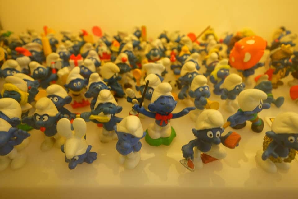 Eine Ansammlung von blauen und weißen Spielzeugfiguren, einige mit Hüten und andere mit Zubehör, drapiert auf einer Fläche.