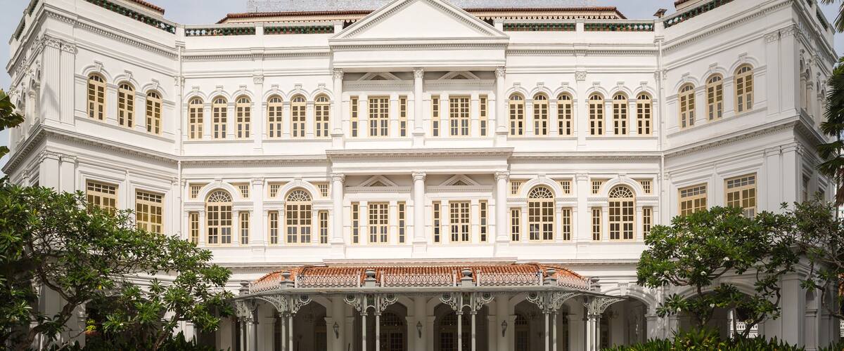 A large white building with a symmetrical facade, columns, and a central entrance with a tiled roof.