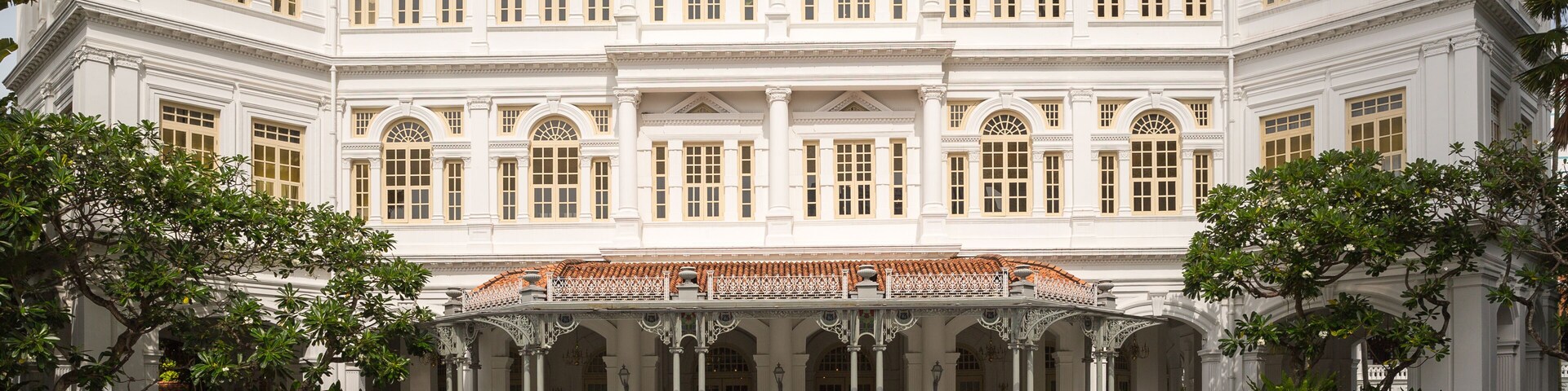 Un edificio grande y blanco con fachada simétrica, columnas y una entrada central con tejado de azulejos.