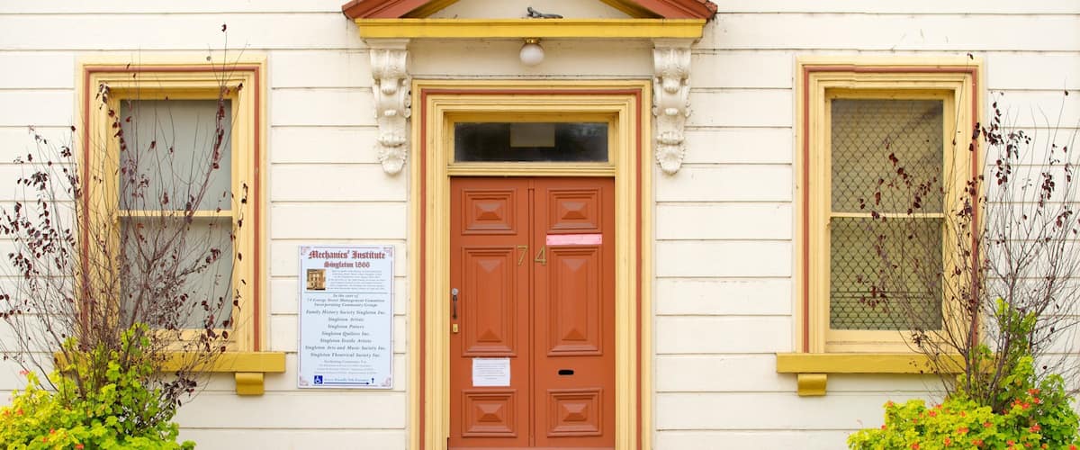 Un edificio con puerta roja, detalles amarillos y un cartel.
