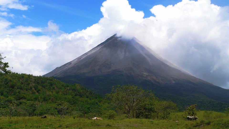 Una montaña con una capa de nubes, rodeada de vegetación verde.