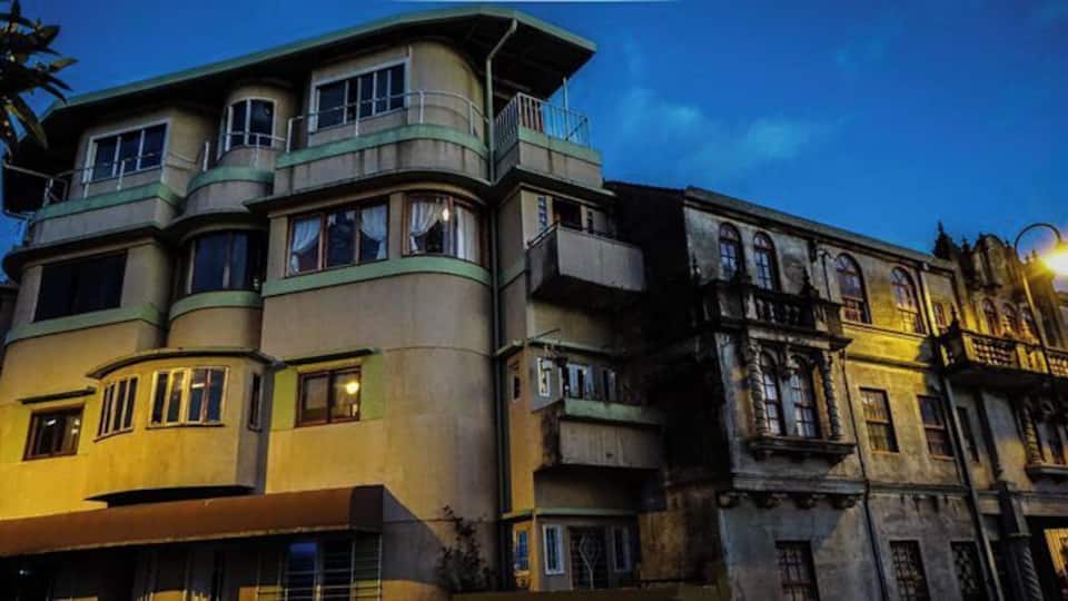A multi-story building with a curved facade, large windows, and a balcony.