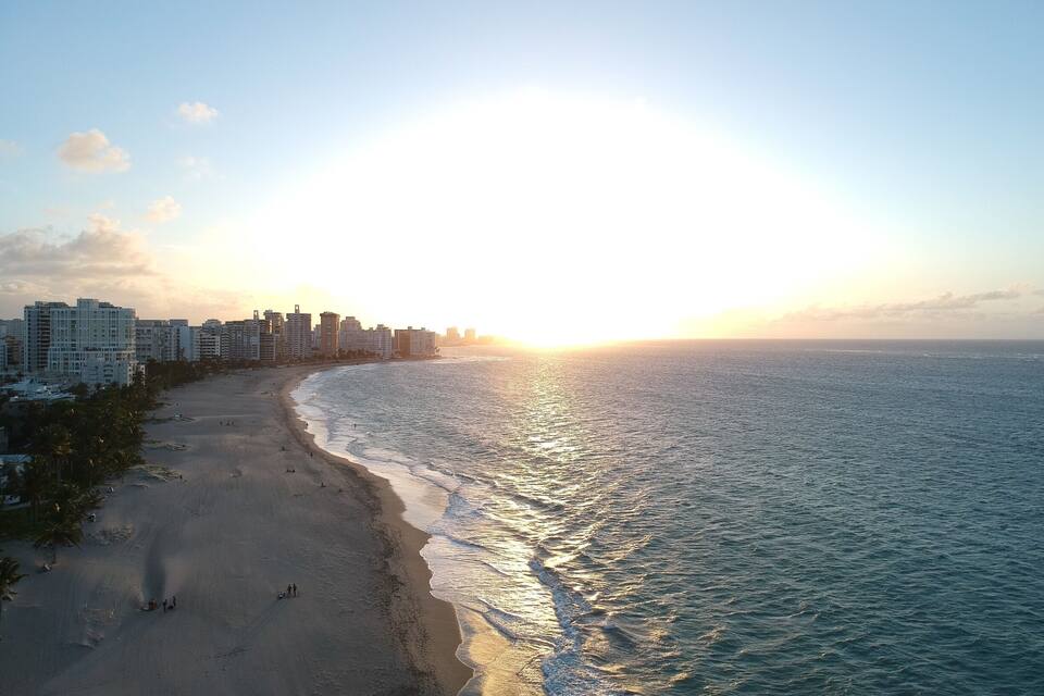 Una playa con el horizonte de una ciudad al atardecer.