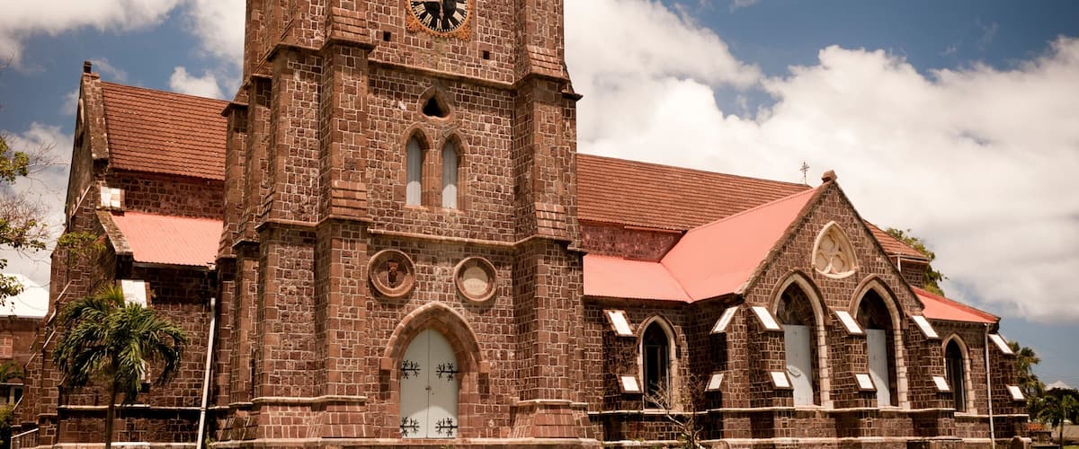 A historic church with a clock tower, arched windows, and a red roof.