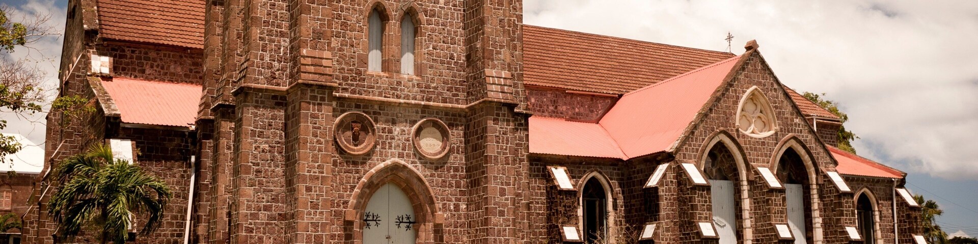 A historic church with a clock tower, arched windows, and a red roof.