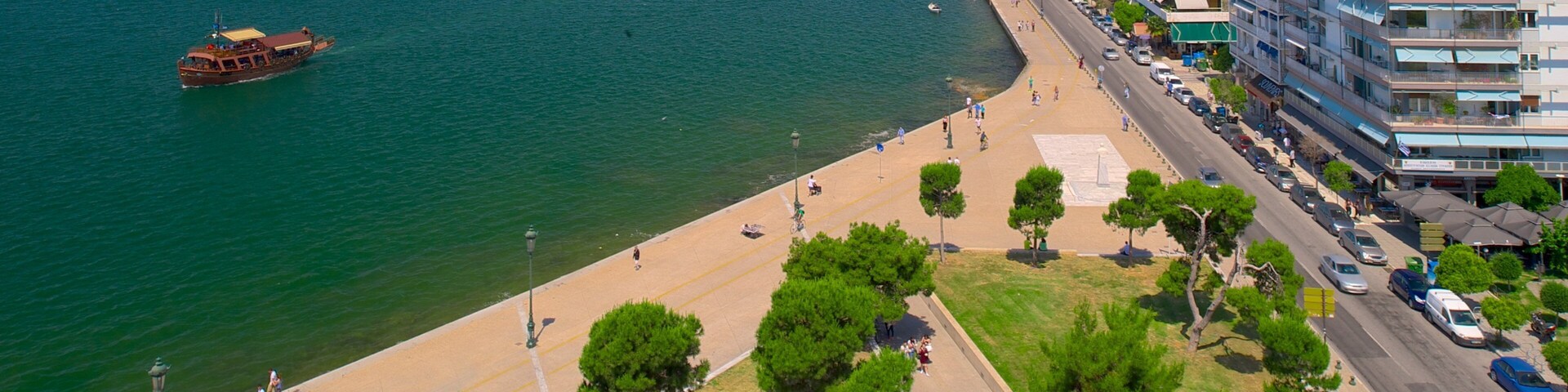 Una ciudad costera con playa, un barco en el agua y edificios altos a lo largo de la orilla.