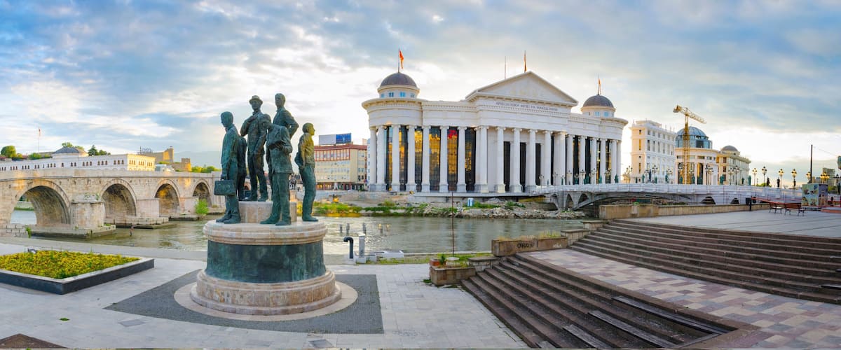 A historic bridge, a statue, and a large white building with columns.