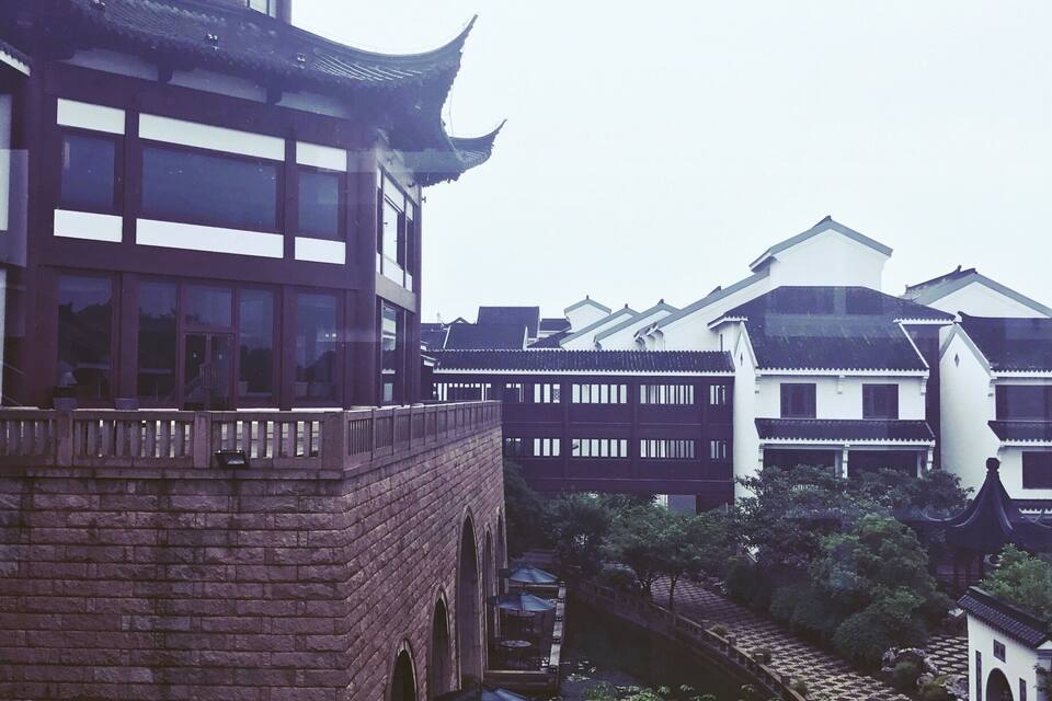 A traditional Chinese building with a multi-tiered roof and a courtyard with a water feature.