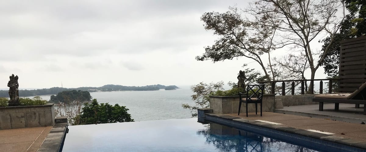 A swimming pool with a view of a body of water and a distant shoreline.