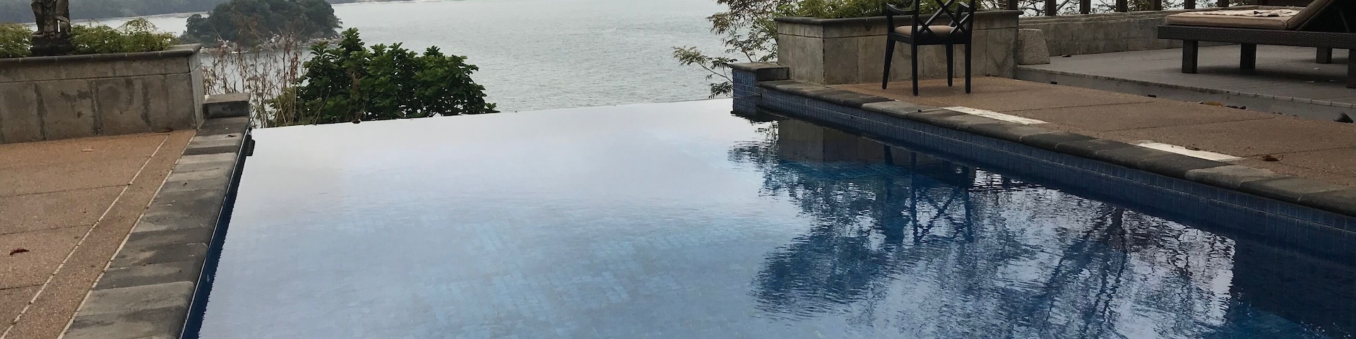 A swimming pool with a view of a body of water and a distant shoreline.