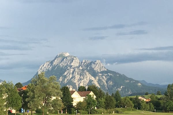 Une montagne, avec un lac au premier plan et des maisons en arrière-plan.