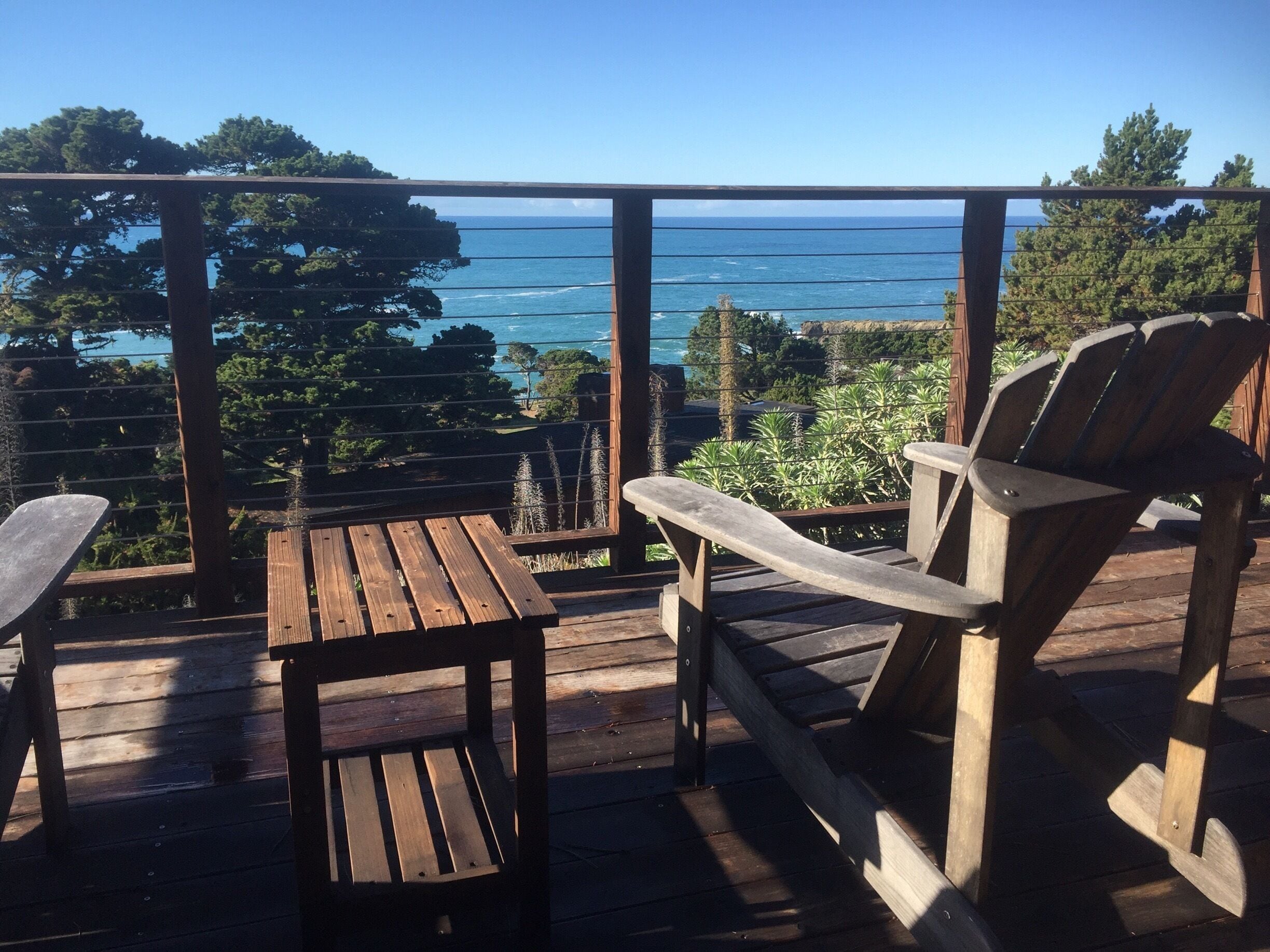 A wooden deck with a view of the ocean and trees.