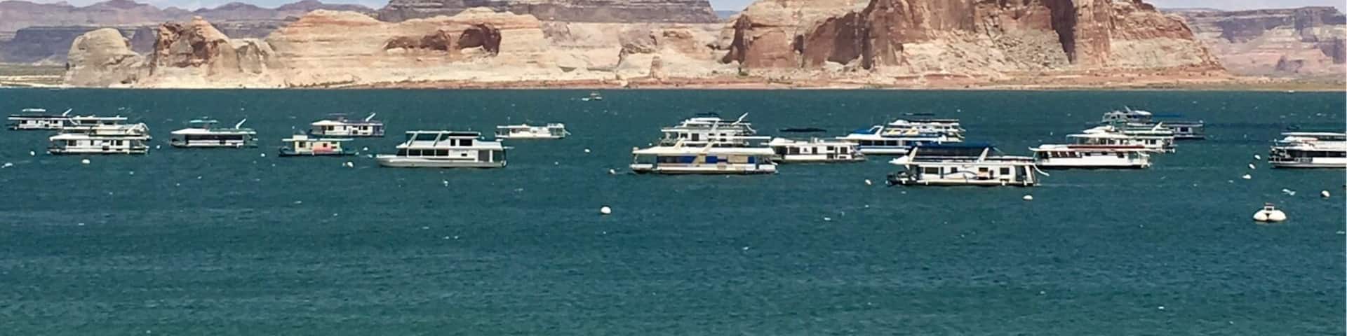 A coastal landscape with boats on the water, rocky cliffs, and a clear sky.
