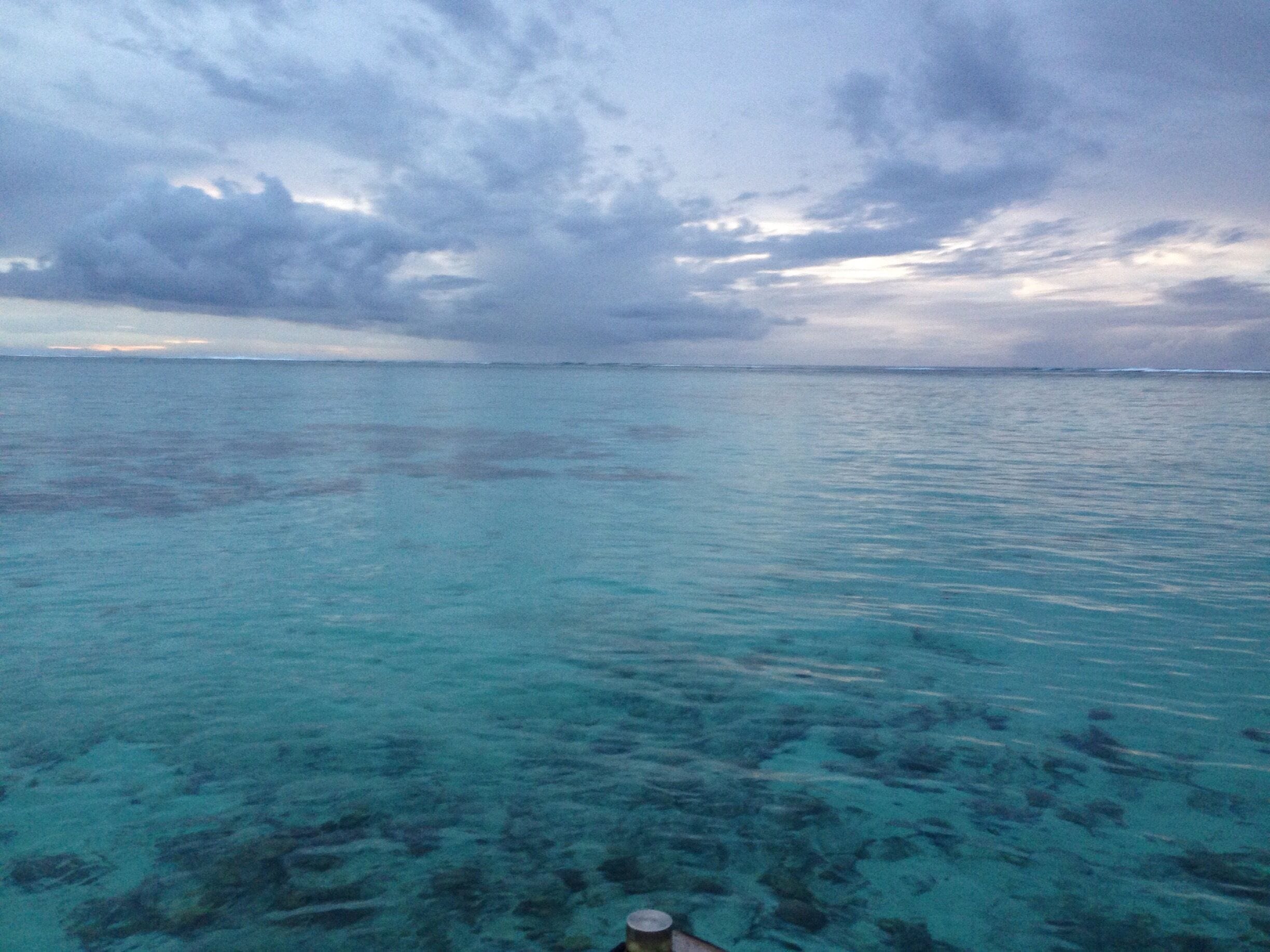 A view of a turquoise sea with clear water and a cloudy sky.
