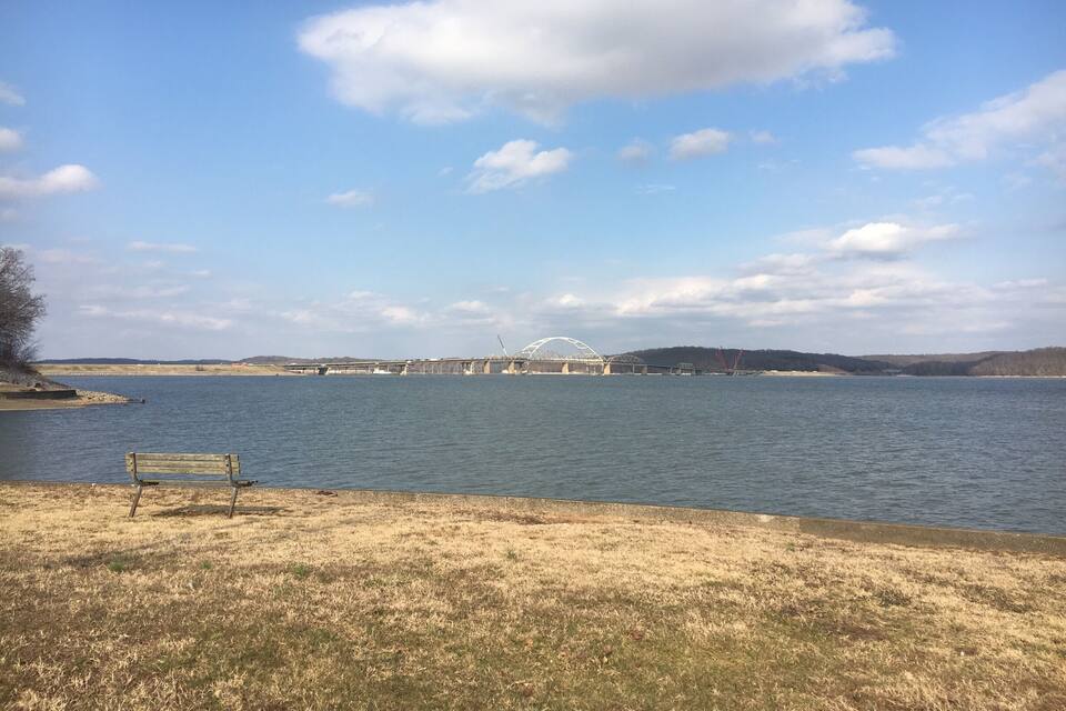 A river with a bridge and a bench on the shore.