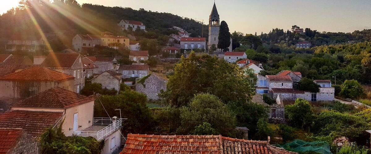 A village with stone buildings and a church with a bell tower.